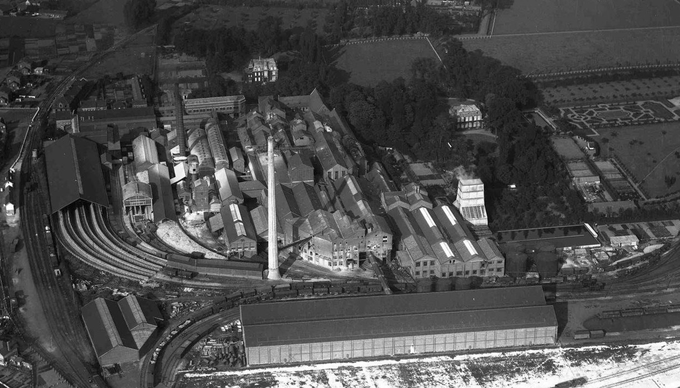 Vue aérienne ancienne de l’usine sucrière de Thumeries, avec le château au milieu des arbres, au-dessus de l’usine